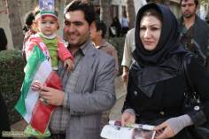 Criança no colo de seu pai com uma foto do líder supremo do Irã, Aiatolá Ali Khamenei e a bandeira do Irã.