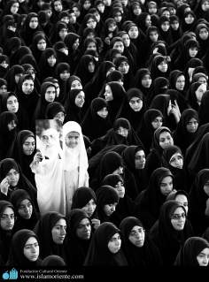 Menina muçulmana segurando a foto do Aiatolá Khomenei em um encontro religioso 